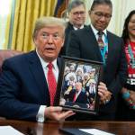 President Donald Trump shows off a gift during and event to sign an executive order establishing the Task Force on Missing and Murdered American Indians and Alaska Natives, in the Oval Office of the White House, Tuesday, Nov. 26, 2019, in Washington. (AP Photo/ Evan Vucci)