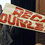 In this March 26, 2019, file photo, protestors unfurl a Recall Dunleavy banner as Gov. Mike Dunleavy, upper left, speaks during a roadshow with Americans for Prosperity in 49th State Brewing Company in Anchorage, Alaska. Dunleavy said he hopes to move past the rancor of his first year in office, amid an unsettled dispute with lawmakers over state spending and threat of a recall effort looming large. The Republican will mark a full year in office Tuesday, Dec. 3. (Bill Roth/Anchorage Daily News via AP, File)