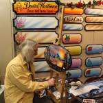David Hartman paints and sells personalized signs at the annual Central Peninsula Hospital Auxiliary Holiday Bazaar in Soldotna, Alaska on Dec. 6, 2019. (Photo by Brian Mazurek/Peninsula Clarion)