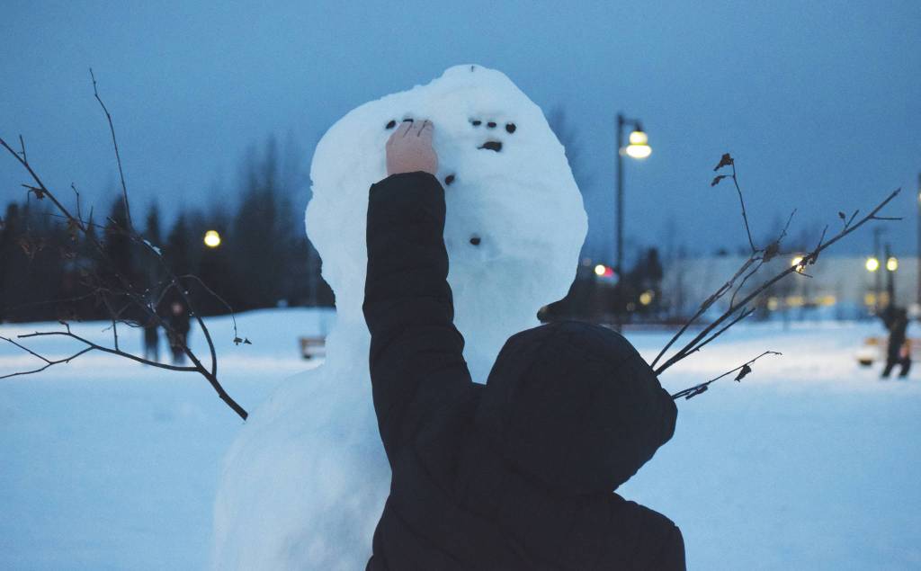 A young boy puts the finishing touches on a snowman Saturday, Dec. 7, 2019, at the Christmas in the Park celebration at Soldotnat Creek Park in Soldotna, Alaska. (Photo by Joey Klecka/Peninsula Clarion)