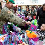 This Dec. 3, 2019, photo shows Alaska National Guard Staff Sgt. Joseph Sallaffie handing a gift bag to Corban Jimmy while Marlene Black looks on during Santas visit to Napakiak, Alaska. The Alaska National Guard brought its Operation Santa Claus to the western Alaska community, which is being severely eroded by the nearby Kuskokwim River. (AP Photo/Mark Thiessen)