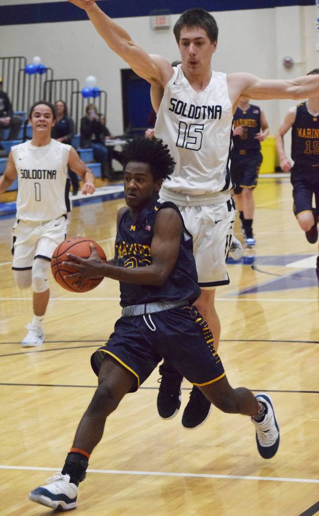 Homers Eyoab Knapp (bottom) drives the lane for a layup under Soldotnas Jersey Truesdell, Friday, Dec. 20, 2019, at the Powerade/Al Howard Tip-Off tournament at Soldotna High School. (Photo by Joey Klecka/Peninsula Clarion)