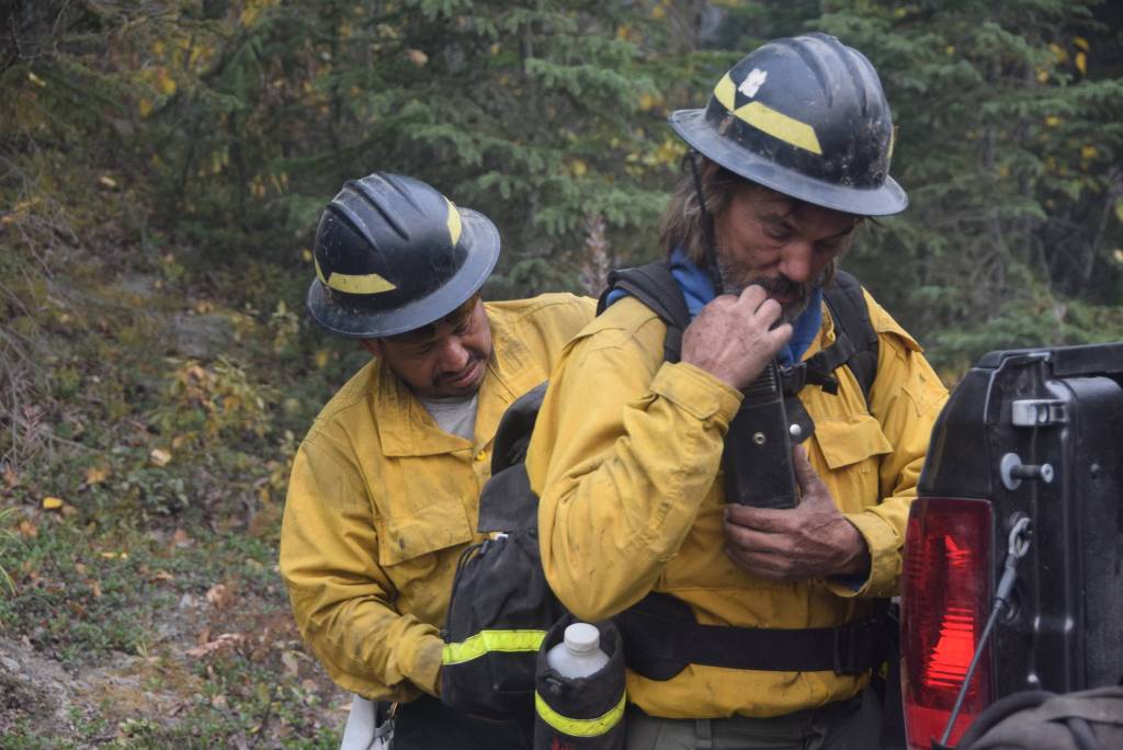 Firefighters with the Snake River Valley firefighting team help each other suit up for the days operations on Skilak Lake Road on Aug. 30, 2019. (photo by Brian Mazurek/Peninsula Clarion)