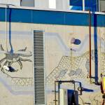 After construction workers removed siding from the facade of the Kenai Municipal Airport, a mural with iconic Kenai images like fishing nets, the St. Nicholas Russian Orthodox chapel and a dog musher, was revealed on Tuesday, Jan. 15, 2019 in Kenai, Alaska. (Photo by Victoria Petersen/Peninsula Clarion)