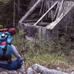 A hiker rests near the remains of an old Surprise Creek mine structure, June 1990. (Photo by Clark Fair)