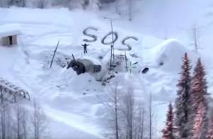 In this image made from video released by the Alaska State Troopers, an aerial helicopter view from Jan. 9, 2020, shows a man waving with distress signal S.O.S. outside Susitna Valley, Alaska. Alaska State Troopers have rescued Tyson Steele, 30, who survived in a makeshift shelter after his remote cabin burned last month. (Alaska State Troopers via AP)