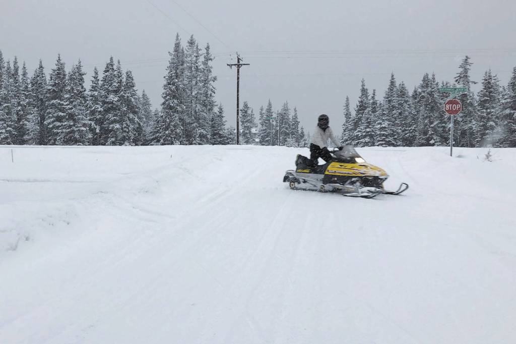 A snowmachine travels down a trail along Kalifornsky Beach Road on Tuesday, Feb. 18, 2020, near Kenai, Alaska. (Photo by Victoria Petersen/Peninsula Clarion)