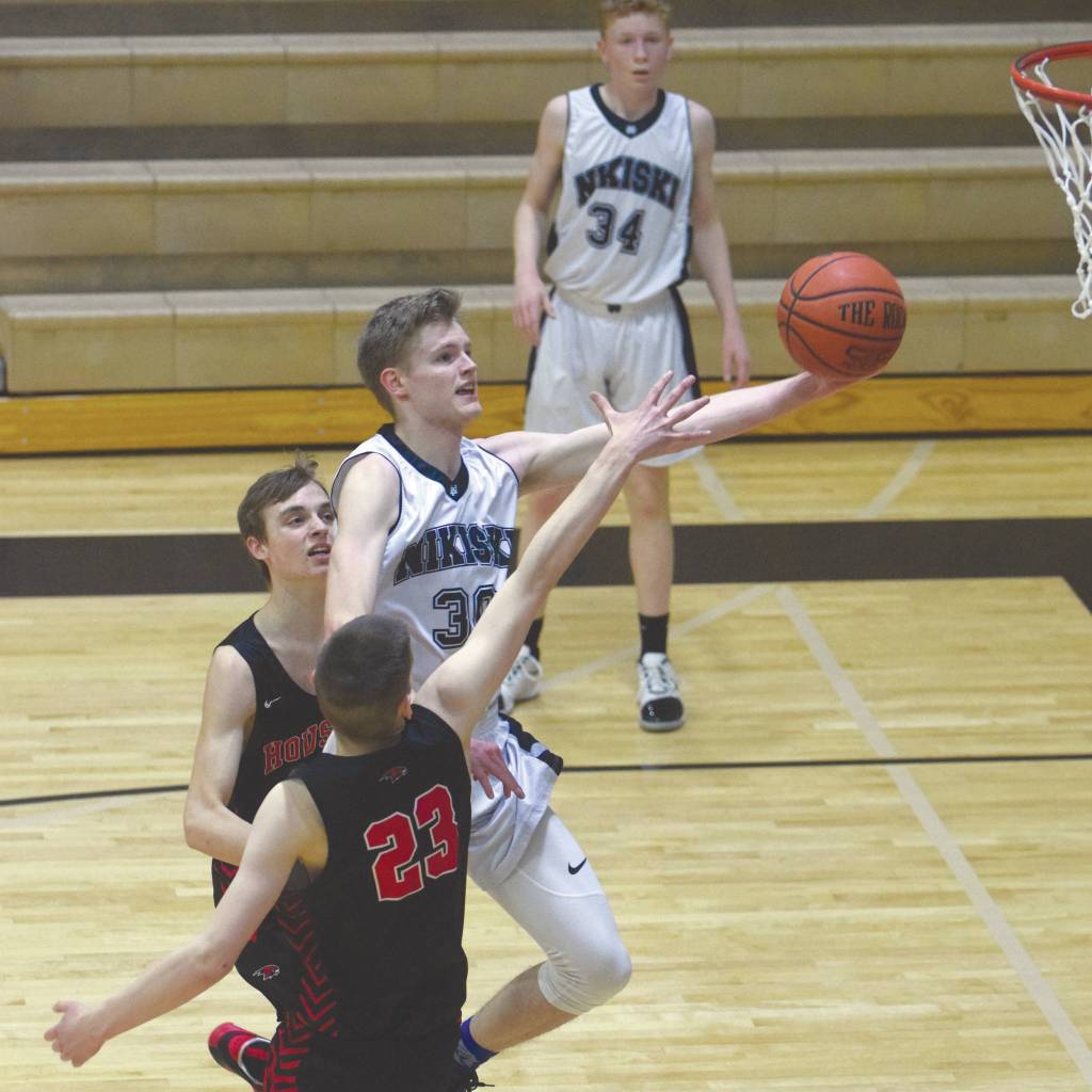 Nikiskis Austin Stafford drives against Houstons Landon Taylor and Hunter Jefferson on Friday, Feb. 22, 2020, at Nikiski High School in Nikiski, Alaska. (Photo by Jeff Helminiak/Peninsula Clarion)