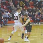 Sewards Sam Koster passes around Kenai Centrals Kayden Daniels in front of a big crowd March 28, 2020, at Kenai Central High School in Kenai, Alaska. The state announced Friday there will be no after-school activiities until March 30, 2020, due to the new coronavirus. (Photo by Jeff Helminiak/Peninsula Clarion)
