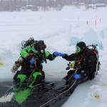 Stephen Robertson, left, and T.J. Cox, right, bump fists before diving into the icy water of Island Lake in Nikiski, Alaska on March 21, 2020. (Photo by Brian Mazurek/Peninsula Clarion)