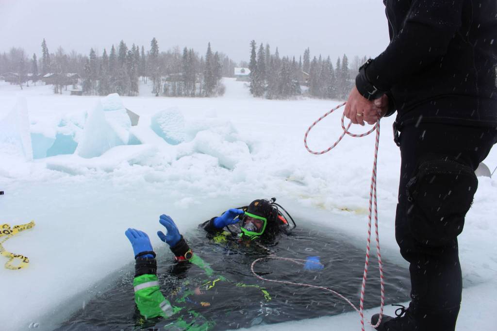 Stephen Robertson, left, and T.J. Cox, center, resurface after a 20-minute ice dive on Island Lake in Nikiski, Alaska on March 21, 2020. Tony Gillham, right, tends the rope line as they resurface. (Photo by Brian Mazurek/Peninsula Clarion)