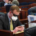 Alaska state Rep. David Eastman sits at his desk on the House floor in Juneau, Alaska, Monday, March 23, 2020. Eastman, a Wasilla Republican, has been critical of the Legislatures planning around the coronavirus. Rep. Sharon Jackson also wore a mask on the House floor Monday. (AP Photo/Becky Bohrer)