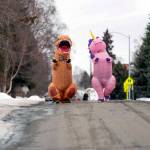 Christine Hohf, wearing a unicorn costume, right,and Andi Correa, wearing a dinosaur costume, walk through South Addition, Wednesday, March 25, 2020 in Anchorage. Hohf, who works as a scrub tech at a surgery center, said her hours were cut due to elective surgeries being put off because of the coronavirus pandemic, and she wanted to do something that would make people smile. (Loren Holmes/Anchorage Daily News via AP)