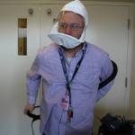 Shayne Pond, Emergency Department Director for Central Peninsula Hospital, demonstrates how to put on a PAPR – Powered air purifying respirator – on April 7, 2020. (Photo by Brian Mazurek/Peninsula Clarion)                                Shayne Pond, Emergency Department Director for Central Peninsula Hospital, demonstrates how to put on a PAPR  Powered air purifying respirator  on Tuesday.