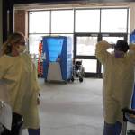 Emergency room technician Angie Sulley, left, and nurse Marcie Duncan put on the personal protective equipment necessary for interacting with patients suspected of having COVID-19 in the ambulance bay outside of the emergency department at Central Peninsula Hospital in Soldotna, Alaska on April 7, 2020. (Photo by Brian Mazurek/Peninsula Clarion)