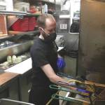 Trevor Pound, a line cook at Buckets Sports Grill in Soldotna, filters the friers Thursday, April 30, 2020. Despite the heat in the kitchen, state regulations say all restaurant employees must wear cloth face masks. Its completely miserable, dude, Pound said. It gets so hot back here I cant breathe without a face mask. But Ive got to pay the bills, so I wear a mask. (Photo by Jeff Helminiak/Peninsula Clarion)