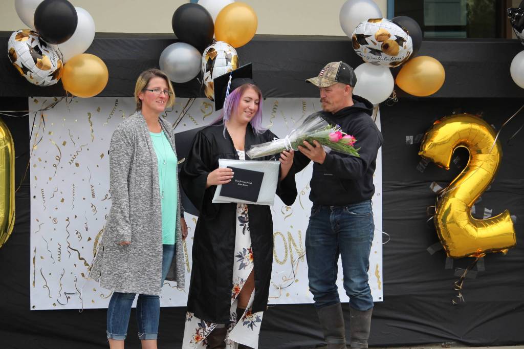 Alexis Kreger takes a bouquet of flowers from her dad, Jesse, during the Connections Homeschool Class of 2020 graduation at Soldotna Elementary School in Soldotna, Alaska on May 21, 2020. (Photo by Brian Mazurek/Peninsula Clarion)