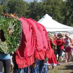 Participants in an aerial art installation march through the Kenai Peninsula Fairgrounds, with a king salmon leading the way, at Salmonfest in Ninilchik.