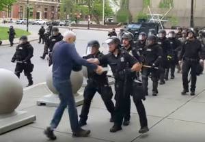 In this image from video provided by WBFO, a Buffalo police officer appears to shove a man who walked up to police Thursday, June 4, 2020, in Buffalo, N.Y. Video from WBFO shows the man appearing to hit his head on the pavement, with blood leaking out as officers walk past to clear Niagara Square. Buffalo police initially said in a statement that a person was injured when he tripped & fell, WIVB-TV reported, but Capt. Jeff Rinaldo later told the TV station that an internal affairs investigation was opened. Police Commissioner Byron Lockwood suspended two officers late Thursday, the mayors statement said. (Mike Desmond | WBFO via AP)
