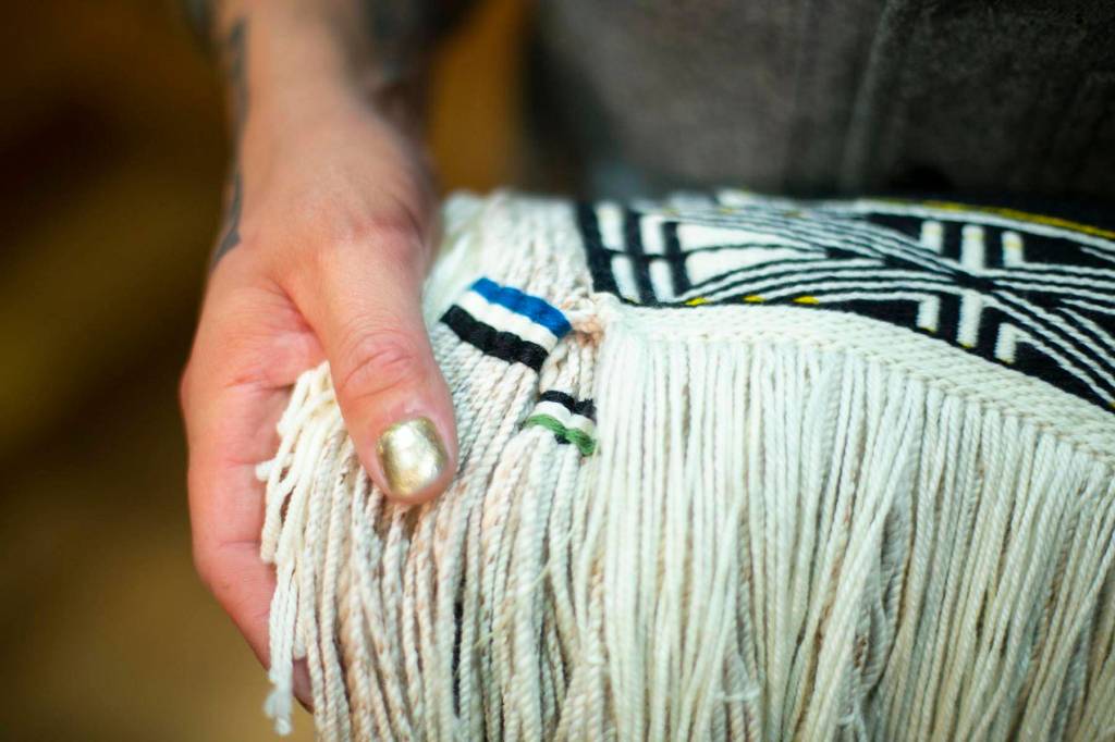 Courtesy photo | Annie Bartholomew                                Ricky Tagaban shows the woven artist signatures on the robe.