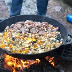 Hash with bacon, potatoes, cheese, sausage, chopped bell peppers and morel mushrooms are prepared on a fire pit, June 19, in the Copper River Valley. (Photo by Victoria Petersen/Peninsula Clarion)