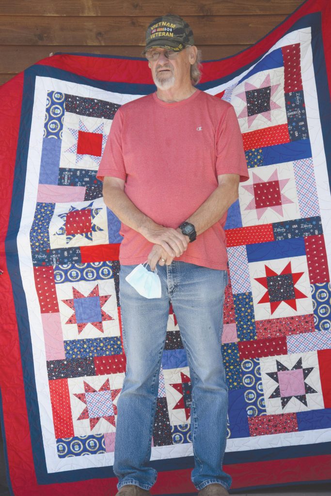 Robert Robertson of Soldotna stands with his Quilt of Valor at Soldotna Creek Park in Soldotna, Alaska, on Saturday, July 4, 2020. (Photo by Jeff Helminiak/Peninsula Clarion)