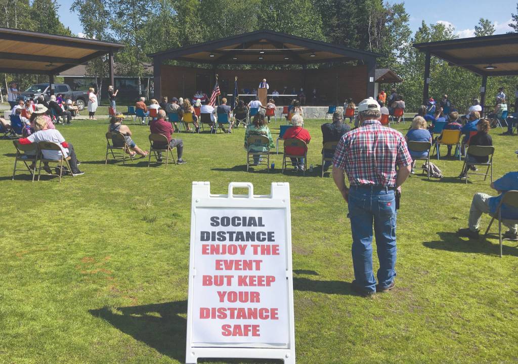 A sign and the spacing of chairs encourage a safe event at the unveiling of Iron Mike on Saturday, July 4, 2020, at Soldotna Creek Park in Soldotna, Alaska. (Photo by Jeff Helminiak/Peninsula Clarion)