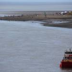 People can be seen dipnetting along the shores of Kenai Beach with a commercial fishing vessel in the foreground on July 10, 2020. (Photo by Brian Mazurek/Peninsula Clarion)