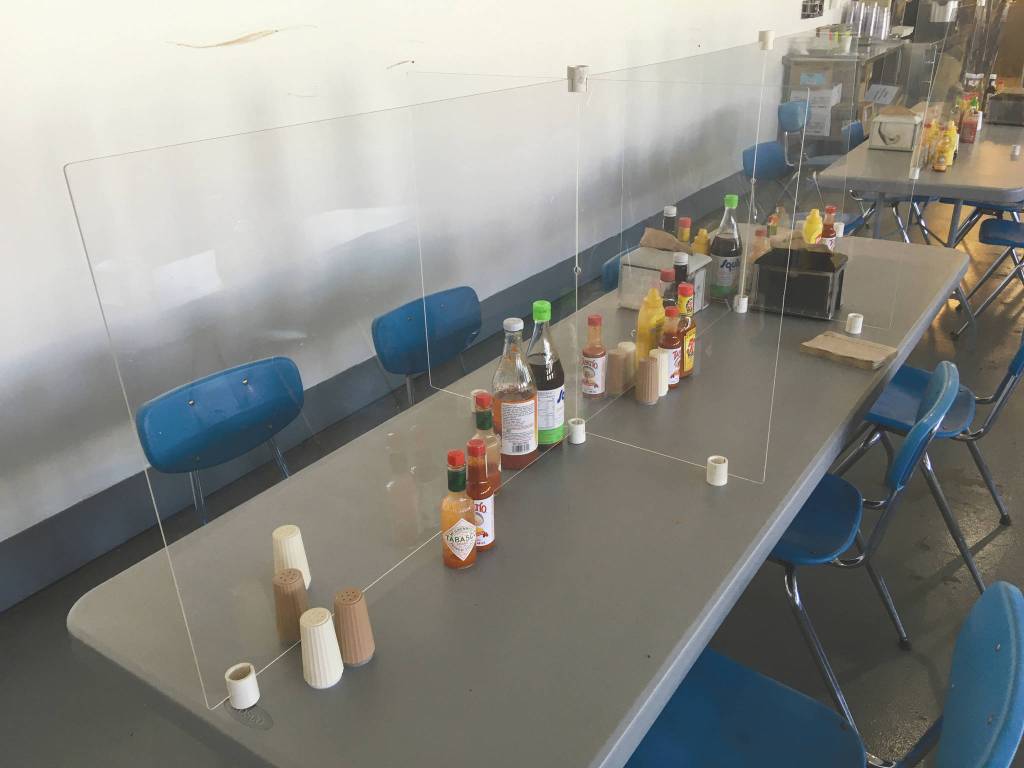 A plexiglass shield divides a dining room table into six, doubling the dining capacity of the table, Tuesday, July 14, 2020, at Pacific Star Seafoods in Kenai, Alaska. (Photo by Jeff Helminiak/Peninsula Clarion)