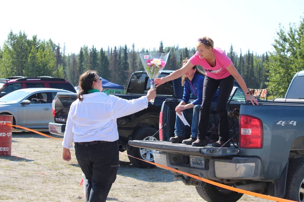 Gracie Rankin of the North Road Rangers hands off a bouquet of peonies to Julie Cosca during the 4-H Junior Market Drive-in Auction at the Soldotna Rodeo Grounds on Aug. 15, 2020. (Photo by Brian Mazurek/Peninsula Clarion)