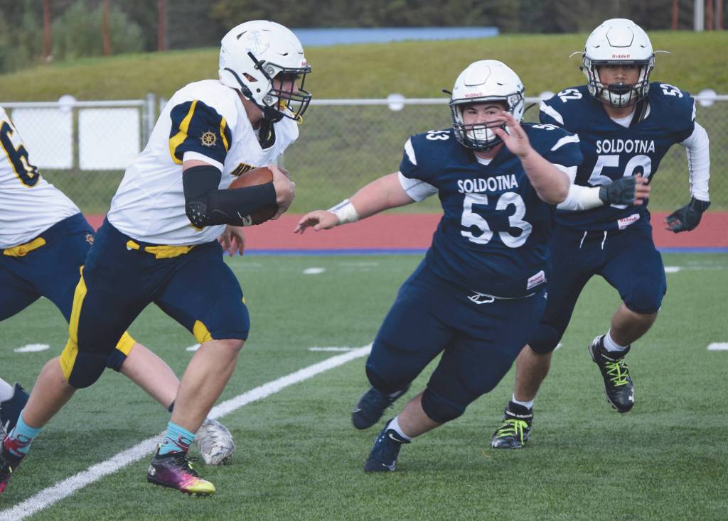 Homer quarterback Carter Tennison runs away from Soldotnas Kaidan Spies and Ethan Lavea on Saturday, Sept. 5, 2020, at Justin Maile Field at Soldotna High School in Soldotna, Alaska. (Photo by Jeff Helminiak/Peninsula Clarion)