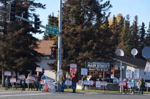 Supporters hold campaign signs at the intersection of Main St. Loop and Kenai Spur Highway in Kenai, Alaska, on Tuesday, Oct. 6. (Photo by Ashlyn OHara/Peninsula Clarion)