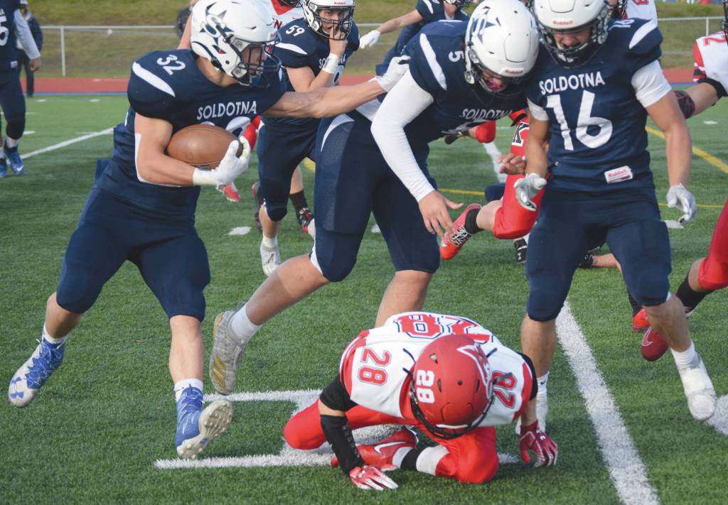 Soldotnas Dennis Taylor follows the blocking of Brock Wilson and Austin Escott past Kenai Centrals James Sparks on Friday, Oct. 9, 2020, at Justin Maile Field in Kenai, Alaska. (Photo by Jeff Helminiak/Peninsula Clarion)