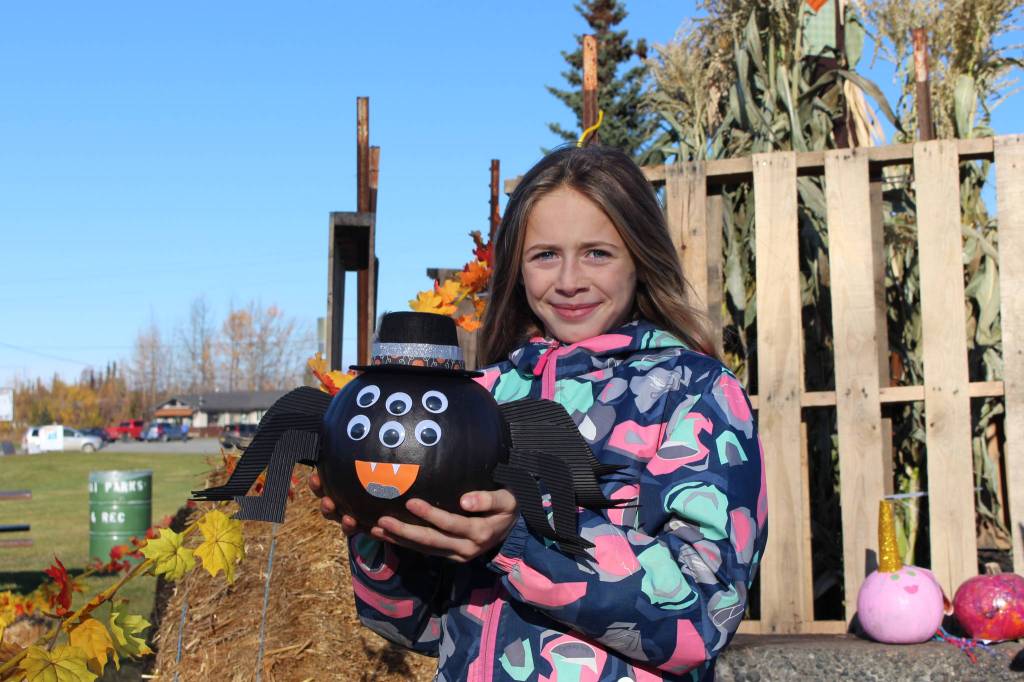 Blakeley Jorgensen, of Kenai, poses with her pumpkin-turned-spider during the 5th annual Kenai Fall Pumpkin Festival in Kenai, Alaska on Oct. 10, 2020. (Photo by Brian Mazurek/Peninsula Clarion)