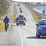 A biker leads a line of cars driving off the Homer Spit at about 1:30 p.m. Monday, Oct. 19, 2020, in Homer, Alaska after a tsunami evacuation order was issued for low-lying areas in Homer. (Photo by Michael Armstrong/Homer New)