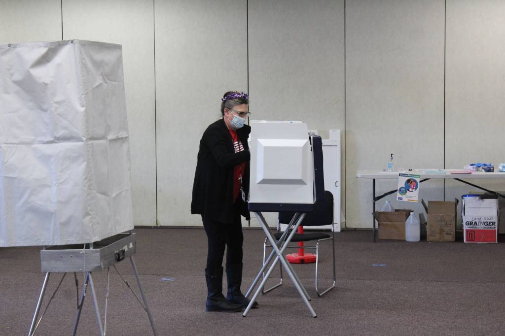 A poll worker disinfects a voting booth at the Soldotna Regional Sports Complex on Tuesday, Nov. 3 in Soldotna, Alaska. (Photo by Ashlyn OHara/Peninsula Clarion)