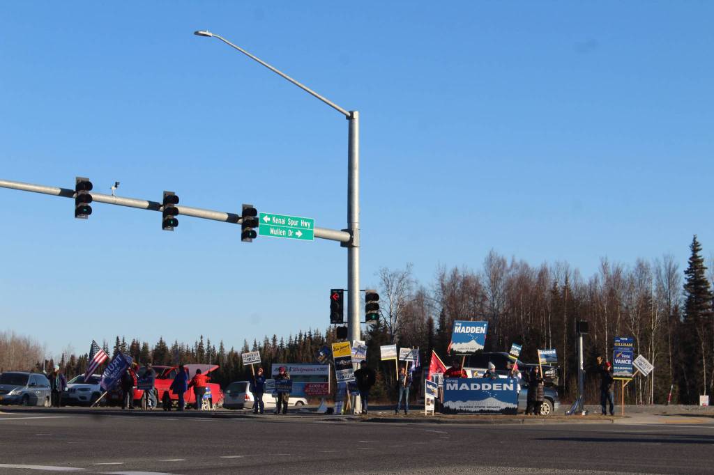 People are seen holding political signs at the intersection of Sterling Hwy. and Kenai Spur Hwy. on Tuesday, Nov. 3 in Soldotna, Alaska. (Photo by Ashlyn OHara/Peninsula Clarion)