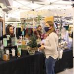 Dharmic Spruce owner Branden Elde, left, of Homer, shows off her wares to Amy Frapp, right, of Soldotna, during the Merry Little Christmas Market at the Peninsula Center Mall in Soldotna, Alaska on Nov. 7, 2020. (Photo by Brian Mazurek/Peninsula Clarion)