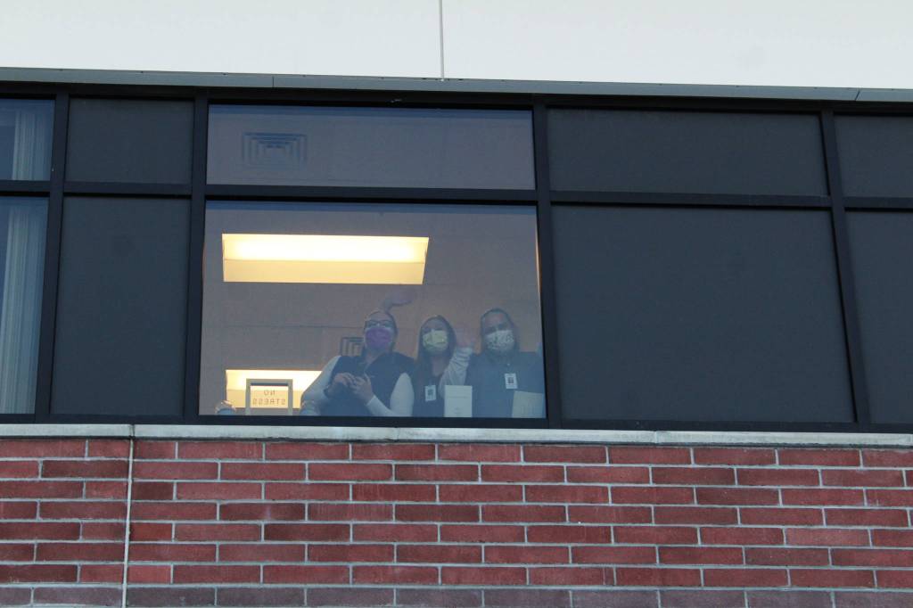 Health care workers wave from inside of Central Peninsula Hospital while awaiting the delivery of the facilitys first shipment of COVID-19 vaccines on Wednesday, Dec. 16, 2020 in Soldotna, Alaska. (Ashlyn OHara/Peninsula Clarion).