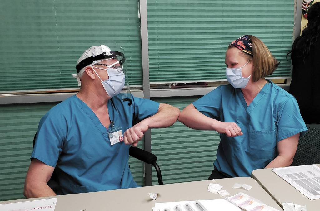 Family practice physician Christina Tuomi, DO, (right) elbow bumps with Emergency Department nurse Steve Hughes (left) after getting Homers first dose of Pfizers COVID-19 vaccine on Thursday, Dec. 17, 2020 at South Peninsula Hospital in Homer, Alaska. Tuomi has been the hospitals medical lead throughout the pandemic. (Photo courtesy Derotha Ferraro/South Peninsula Hospital)