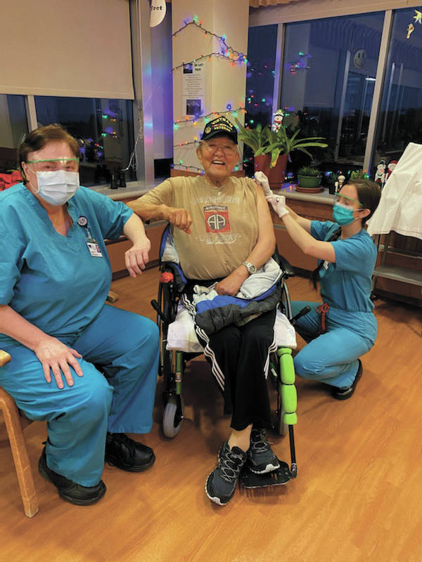 Larry Young, a resident of South Peninsula Hospitals Long Term Care wing, is the first resident to be inoculated with a dose of the Pfizer COVID-19 vaccine on Thursday, Dec. 17, 2020 at the nursing home in Homer, Alaska. Administering his shot is nurse practitioner Rachael Kincaid (right), while Long Term Care Medical Director Teresa Johnson, MD, stands by (left). (Photo courtesy Derotha Ferraro/South Peninsula Hospital)
