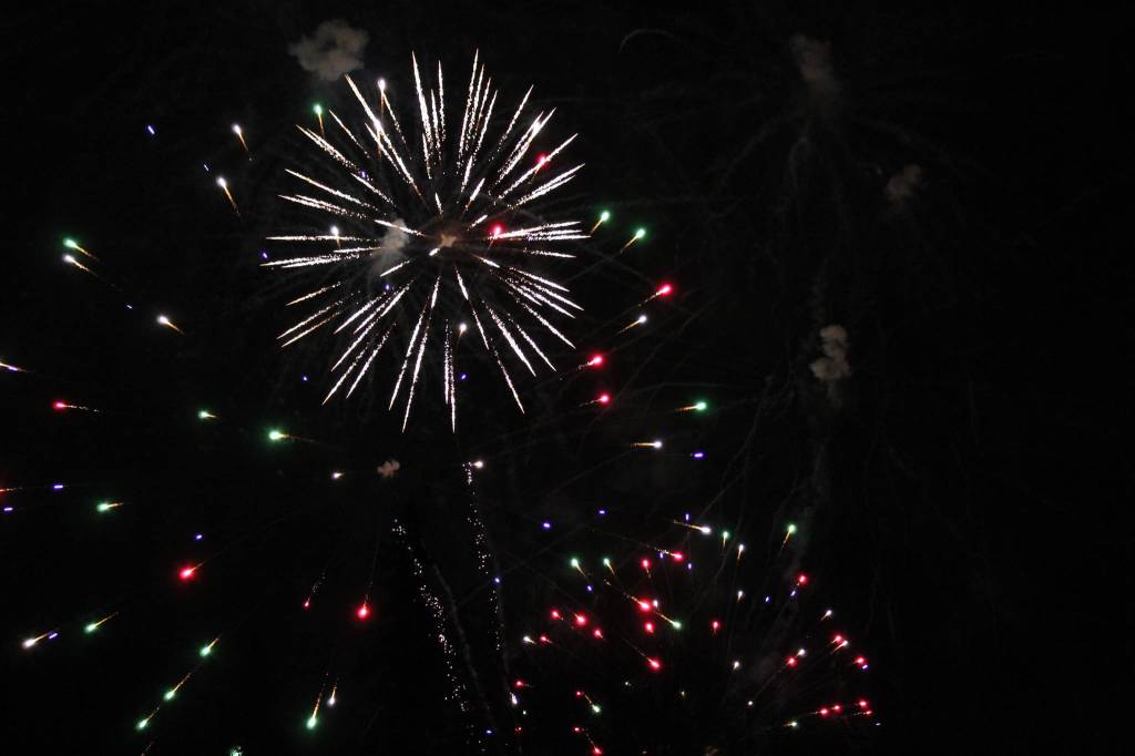 Fireworks are seen above cars at the Soldotna Regional Sports Complex on Friday, Dec. 18 in Soldotna, Alaska. (Ashlyn OHara/Peninsula Clarion)