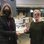 Catherine Pusich, left, hands a check from the Juneau Education Support Staff to Adrianne Schwartz to clear all money owed for school meals at Thunder Mountain High School on Dec. 21, 2020. (Michael S. Lockett / Juneau Empire)
