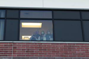 Ashlyn OHara/Peninsula Clarion
Health care workers wave from inside of Central Peninsula Hospital while awaiting the delivery of the facilitys first shipment of COVID-19 vaccines on Dec. 16 in Soldotna.