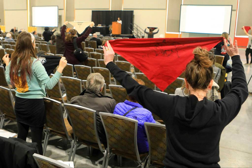 In this Feb. 11, 2019 file photo, protesters hold up flags during a public hearing on a draft environmental plan on proposed petroleum leasing within Alaskas Arctic National Wildlife Refuge in Anchorage, Alaska. Conservationists will try to persuade a U.S. judge to stop the Trump administration from issuing leases to oil and gas companies in the Arctic National Wildlife Refuge. The Anchorage Daily News reported that the videoconference Monday, Jan. 4, 2021, in U.S. District Court in Anchorage is expected to determine whether the Bureau of Land Management can open bids in an online lease sale scheduled for Wednesday. The agency has offered 10-year leases on 22 tracts covering about 1,563 square miles in the coastal plain, which accounts for about 5% of the refuges area. (AP Photo/Dan Joling, File)