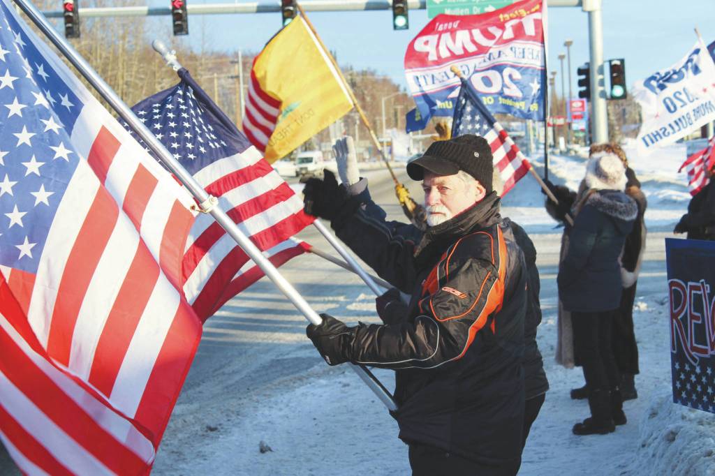 Ron Henry holds an American flag at the intersection of Kenai Spur and Sterling highways on Wednesday, Jan. 6 in Soldotna. (Ashlyn OHara/Peninsula Clarion)