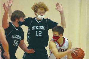Nikiski's Drew Handley and Brady Bostic defend Kenai Central's Bridger Beck on Saturday, Jan. 23, 2021, at Kenai Central High School in Kenai, Alaska. (Photo by Jeff Helminiak/Peninsula Clarion)