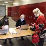 Julie Denison, member of the Kenai Peninsula Boroughs Incident Management Team, and Beth Wilson, pharmacy technician at Soldotna Professional Pharmacy, sign in Kenai Peninsula resident Lee Sparlin for her COVID-19 vaccine appointment at the Soldotna Prep School in Soldotna, Alaska on Jan. 23, 2021. (Photo by Brian Mazurek/Peninsula Clarion)