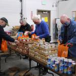 Volunteers prepare bags of shelf stable food to distribute during the upcoming Project Homeless Connect event at the Kenai Peninsula Food Bank in Soldotna, Alaska on Jan. 23, 2021. Pictured, from left: Bill Kelley, Kathy Gensel, Troy Castimore and Pat Young (Photo by Brian Mazurek/Peninsula Clarion)