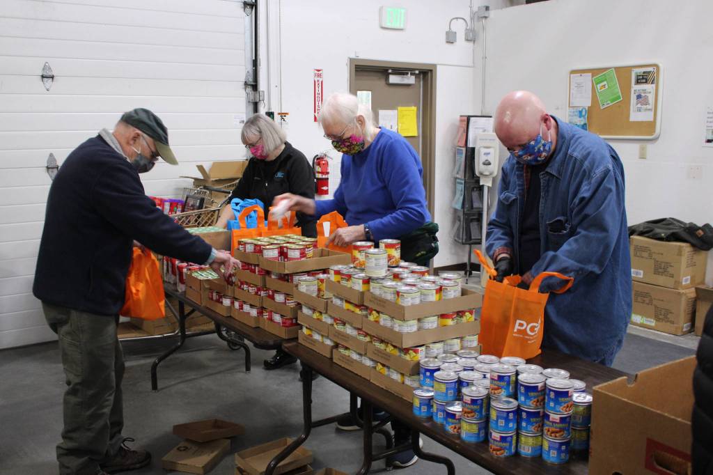 Volunteers prepare bags of shelf stable food to distribute during the upcoming Project Homeless Connect event at the Kenai Peninsula Food Bank in Soldotna, Alaska on Jan. 23, 2021. Pictured, from left: Bill Kelley, Kathy Gensel, Troy Castimore and Pat Young (Photo by Brian Mazurek/Peninsula Clarion)